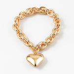 Gold chain bracelet with a puffy heart-shaped charm on a white background