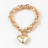 Gold chain bracelet with a puffy heart-shaped charm on a white background