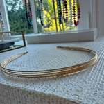 Gold headband on a textured surface with colorful beads in the background