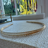 Gold headband on a textured surface with colorful beads in the background