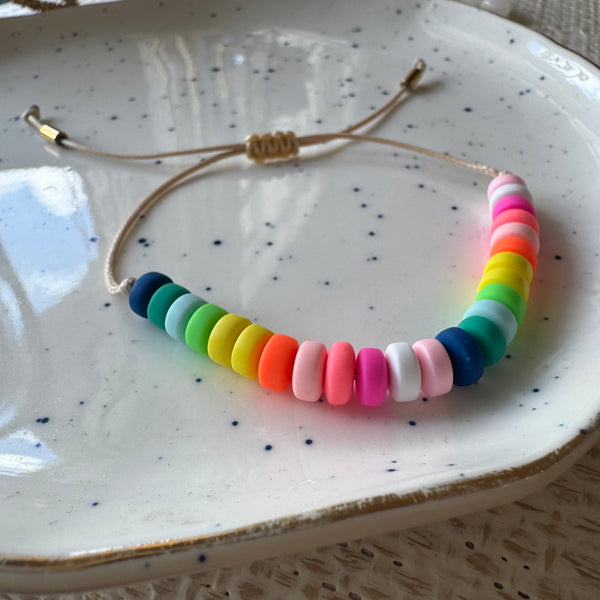 Picture of a cord bracelet with brightly colored resin beads in blue, greens, yellow, orange, pinks and white.