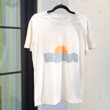 A plain white shirt with an image of an orange sun rising over an ocean 