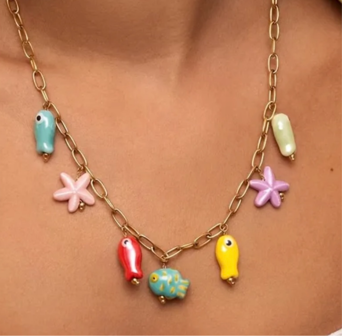This image features a vibrant and colorful ocean charm necklace, displayed on a model. The necklace is crafted with a shiny gold-tone chain and is adorned with an array of bright, ocean-themed charms.