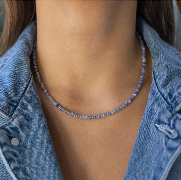Picture of model wearing a small denim blue colored beaded necklace.