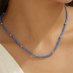 Model displaying delicate blue bead necklace with accenting gold spacer beads.