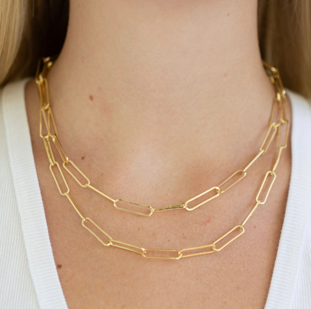 Double layer rectangle gold chain necklace on a person wearing a white top