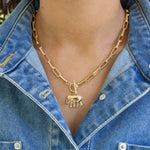 Gold rectangle chain necklace with a toggle clasp and an elephant pendant worn by a person in a denim jacket.