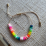 Picture of a cord bracelet with brightly colored resin beads in blue, greens, yellow, orange, pinks and white.