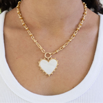 Large link gold necklace chain with a large central gold clasp and large white enamel heart pendant.