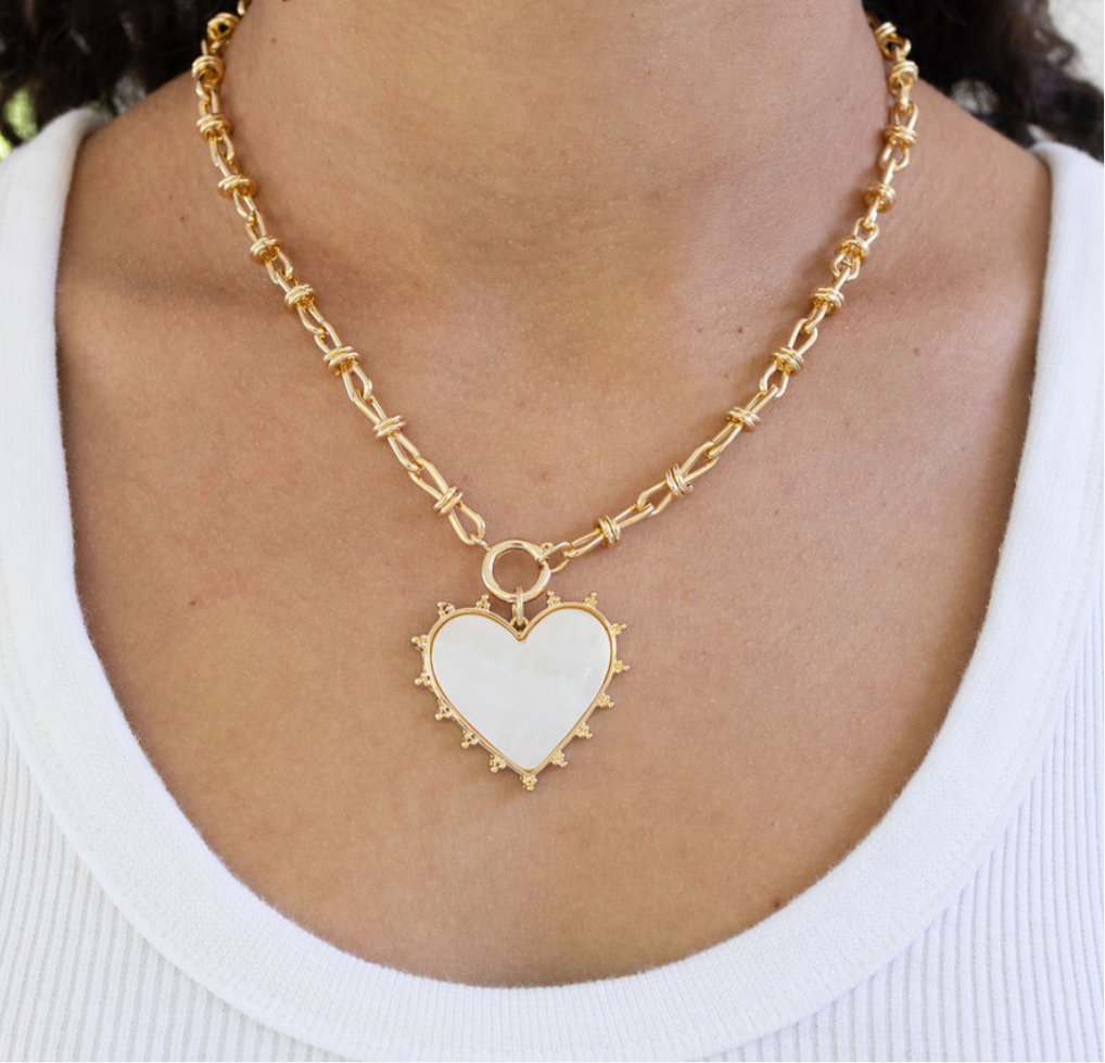Large link gold necklace chain with a large central gold clasp and large white enamel heart pendant.