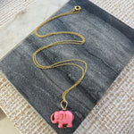 Picture of a dainty gold chain with a pink elephant charm.