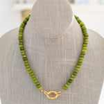 Green beaded necklace with a gold clasp in front.