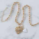 Picture of gold toggle chain with a large heart pendant with diamond at its center. Necklace also has a white heart pendant.