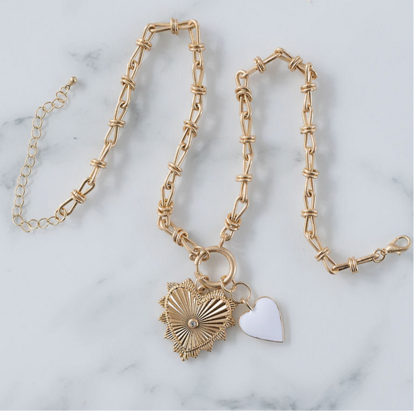 Picture of gold toggle chain with a large heart pendant with diamond at its center. Necklace also has a white heart pendant.