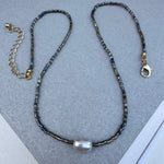 Dainty black shiny seed bead necklace with a large freshwater Pearl at its center.
