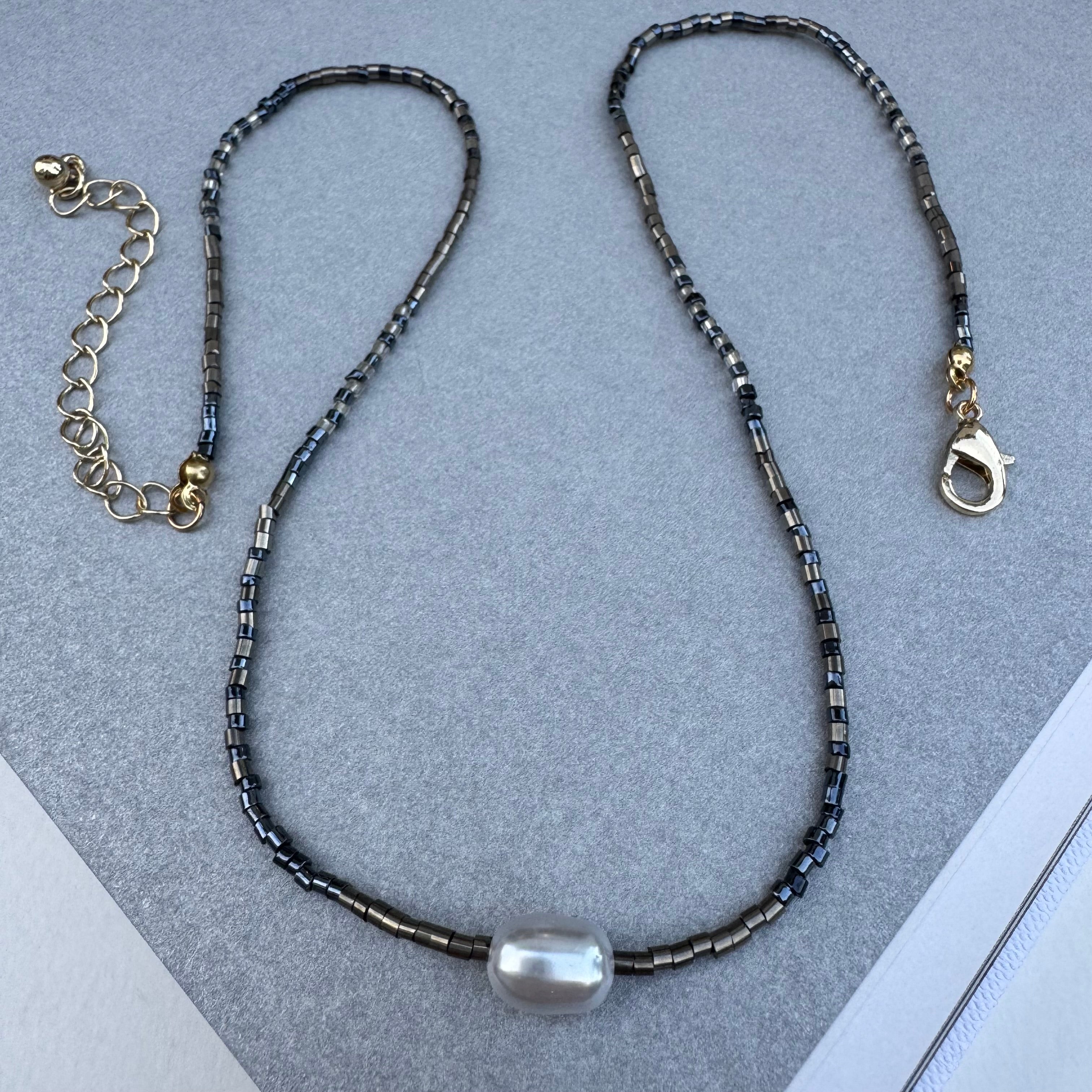 Dainty black shiny seed bead necklace with a large freshwater Pearl at its center.