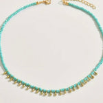 Picture of small turquoise bead necklace with tiny gold dangling accent beads at the front.