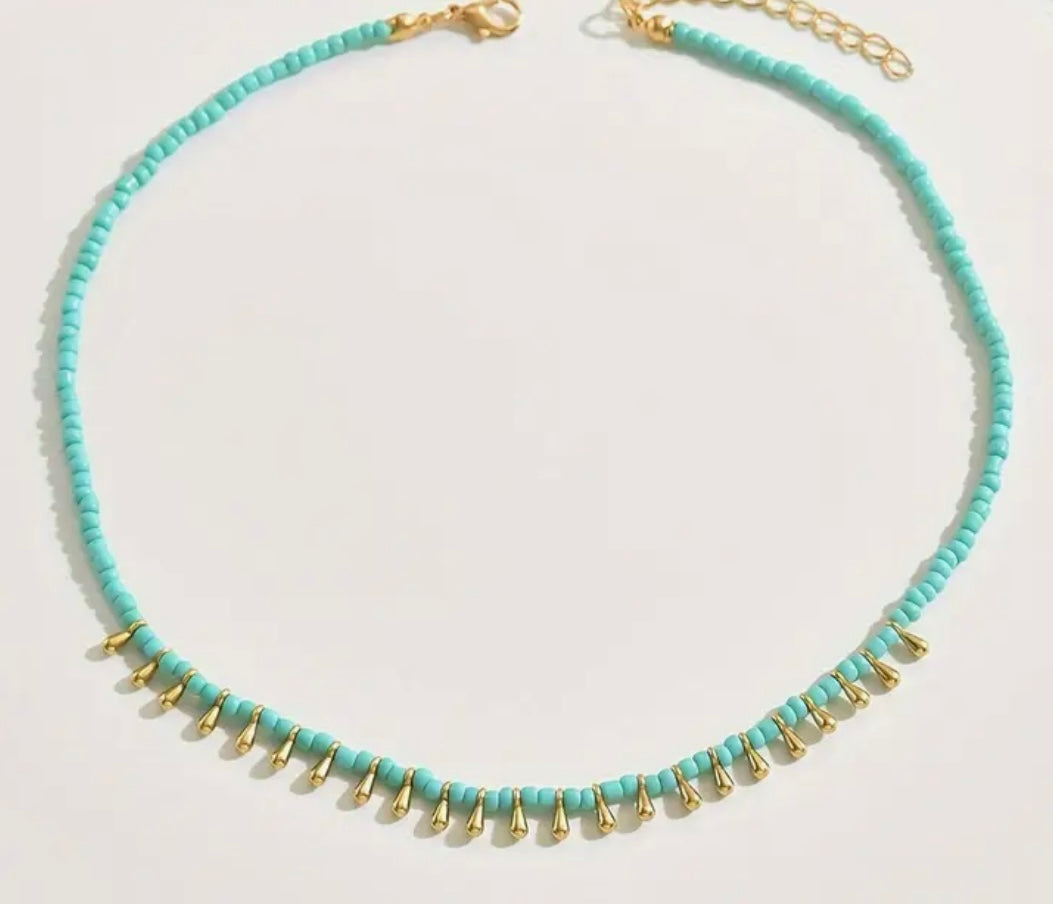 Picture of small turquoise bead necklace with tiny gold dangling accent beads at the front.