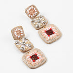 A set of dangle earrings with three sections. Top square is woven in beige with white beads, the second is a beige woven square with white string and clear stones and the third section is a woven square with beige, white and brown strings and pink beads.