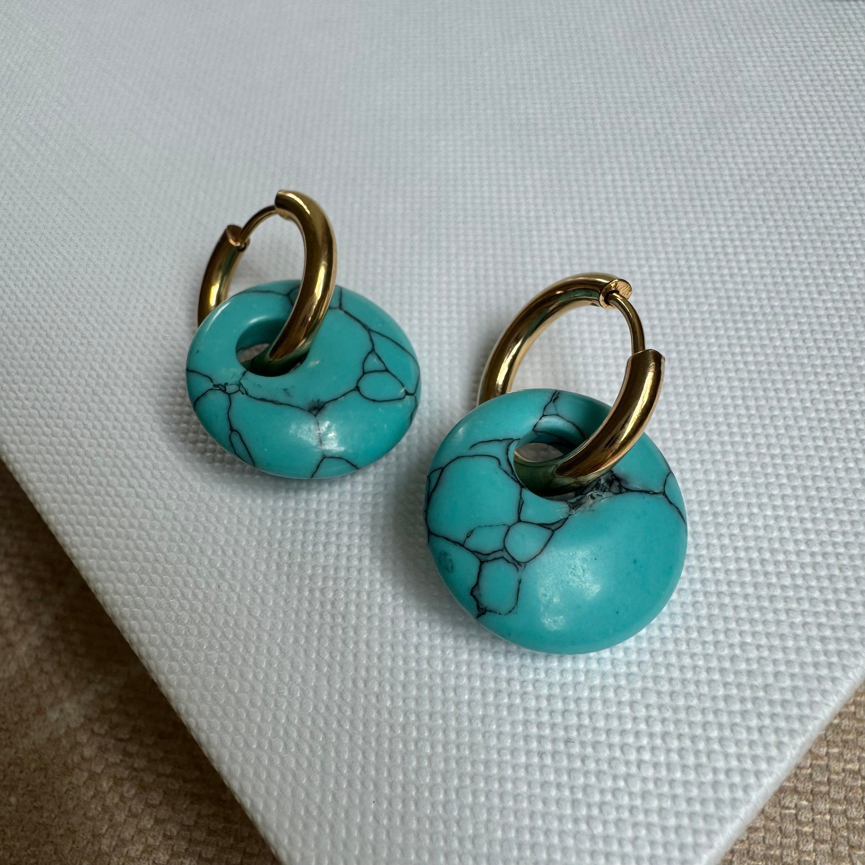 Small gold hoop threaded through a turquoise disc bead.