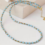 Necklace with light blue stone beads and gold accents on a white background