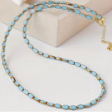 Necklace with light blue stone beads and gold accents on a white background