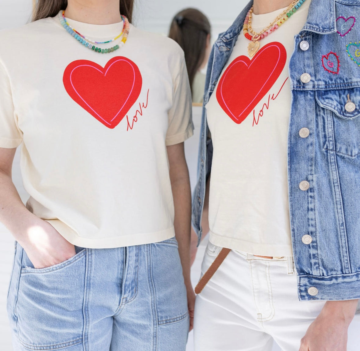 Two individuals wearing beige t-shirts with a red heart and the word 'love' printed on them.