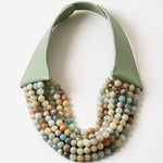 Picture of a six strand semi precious Gemstone beaded bracelet in earthy tones with a green leather strap.