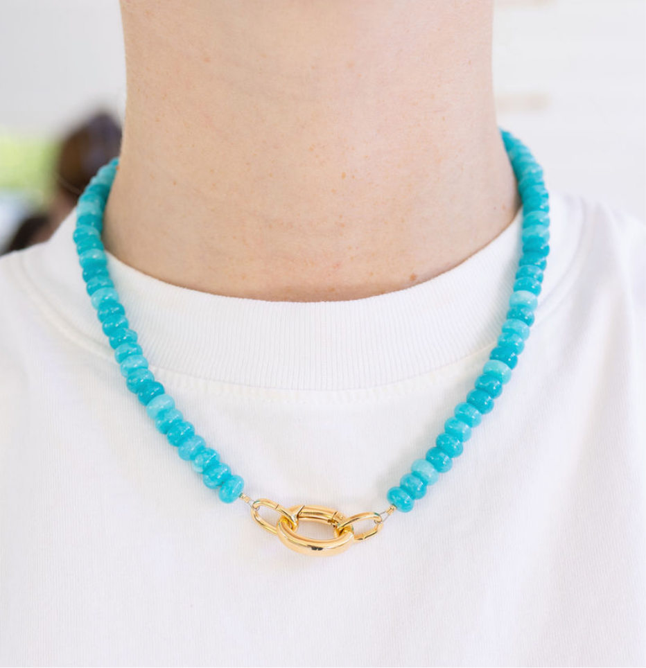 Turquoise beaded necklace with a gold clasp worn by a person on a white background