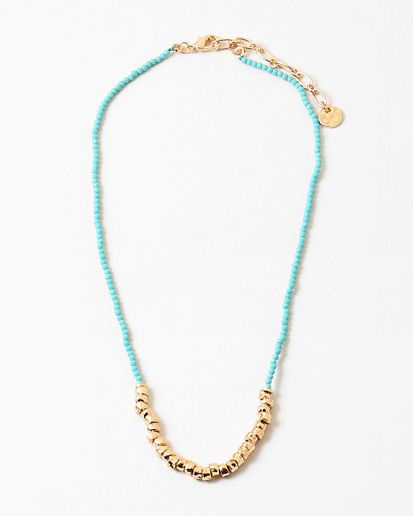 Blue bead necklace with gold beads at its center and a gold clasp.