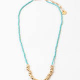 Blue bead necklace with gold beads at its center and a gold clasp.