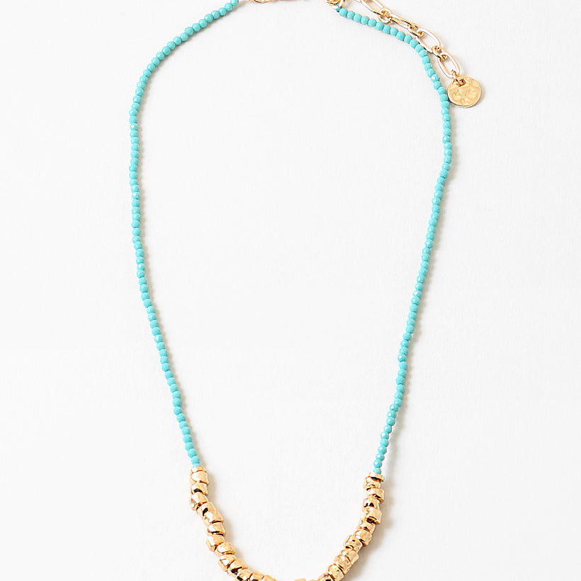 Blue bead necklace with gold beads at its center and a gold clasp.