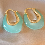 Picture of a set of earrings that are sea green hoops with gold insides.