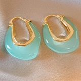 Picture of a set of earrings that are sea green hoops with gold insides.