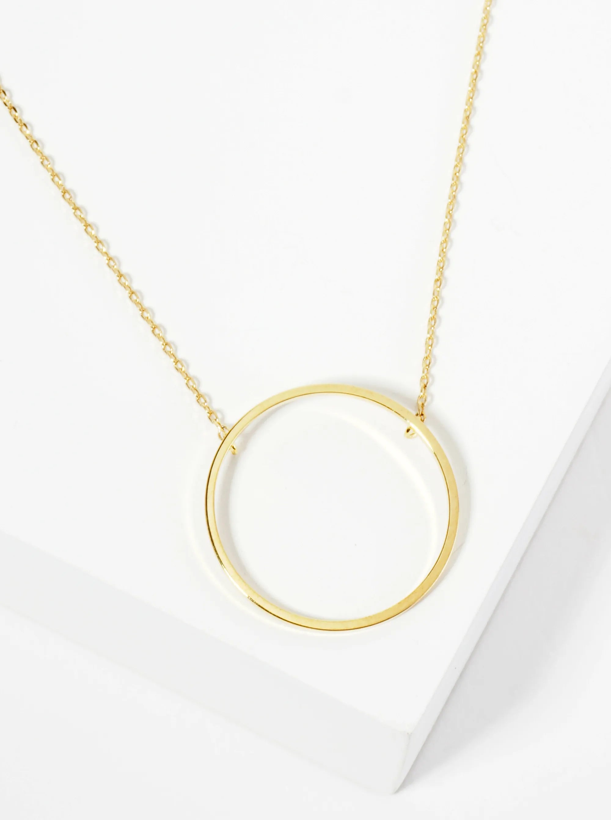 Gold necklace with a circular pendant on a white background