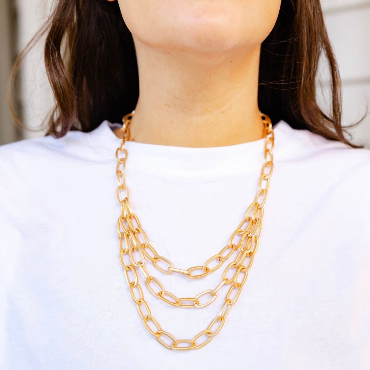 A girl wearing a multi layered gold chained necklace