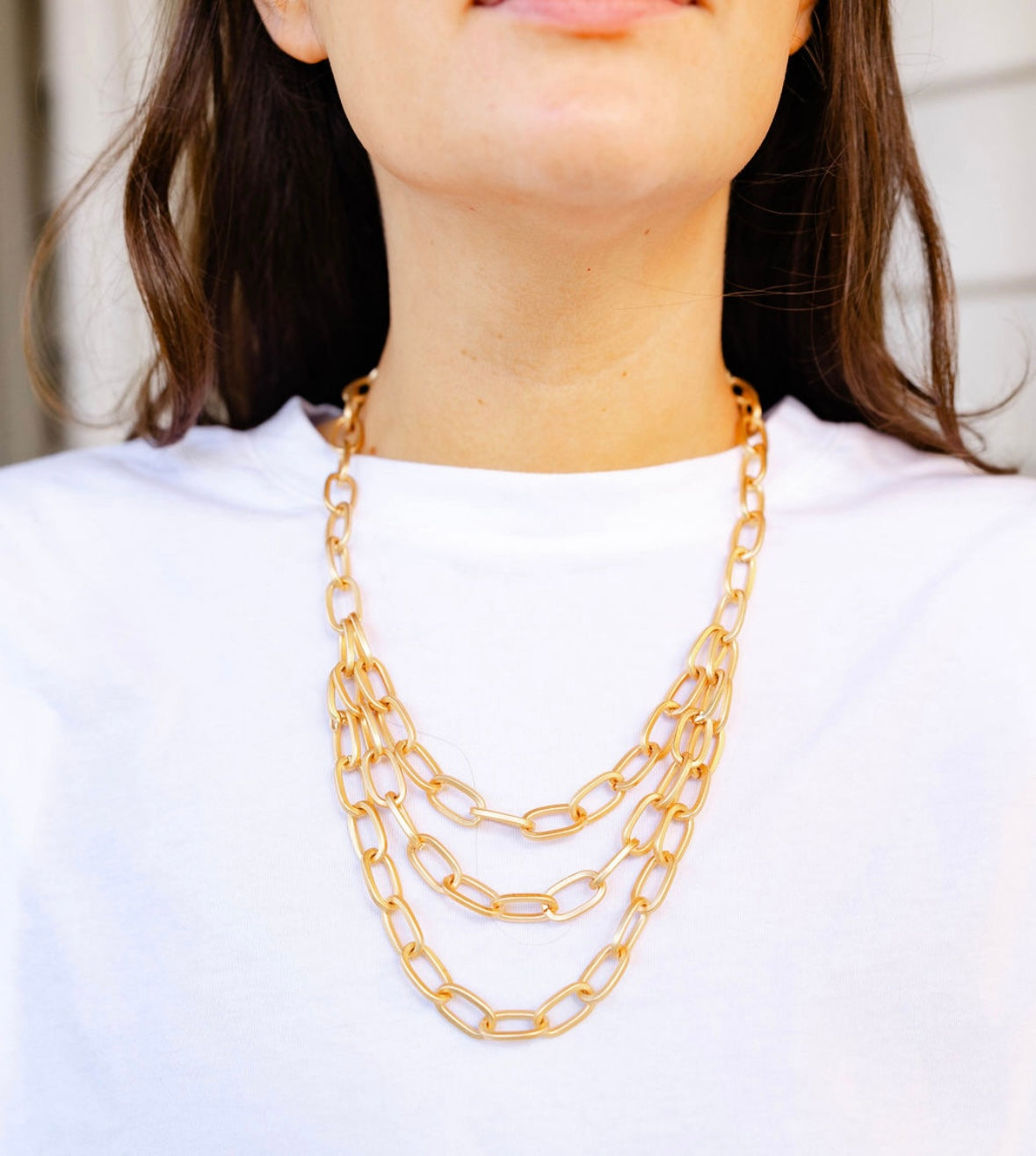 A girl wearing a multi layered gold chained necklace