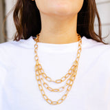 A girl wearing a multi layered gold chained necklace