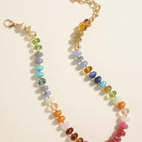 Multicolored beaded necklace with a gold chain on a light background