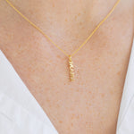 Picture of a woman's neck wearing a a very fine gold chain with a delicate pendant reading "Mama".