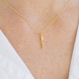 Picture of a woman's neck wearing a a very fine gold chain with a delicate pendant reading "Mama".