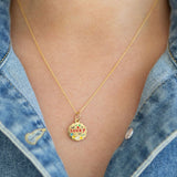 Gold necklace with a 'lucky' pendant worn by a person in a denim jacket.
