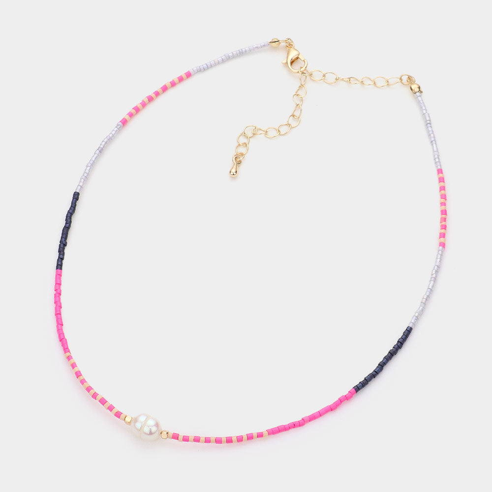 Necklace with pink, clear and blue beads with a fresh water pearl on a white background