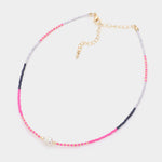 Necklace with pink, clear and blue beads with a fresh water pearl on a white background