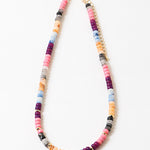 Colorful beaded necklace in pinks, blues, corals and reds with a gold chain and spacers on a white background