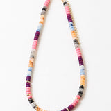 Colorful beaded necklace in pinks, blues, corals and reds with a gold chain and spacers on a white background