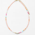 Necklace with multicolored beads in pinks, blues and whites with a freshwater pearl on a white background