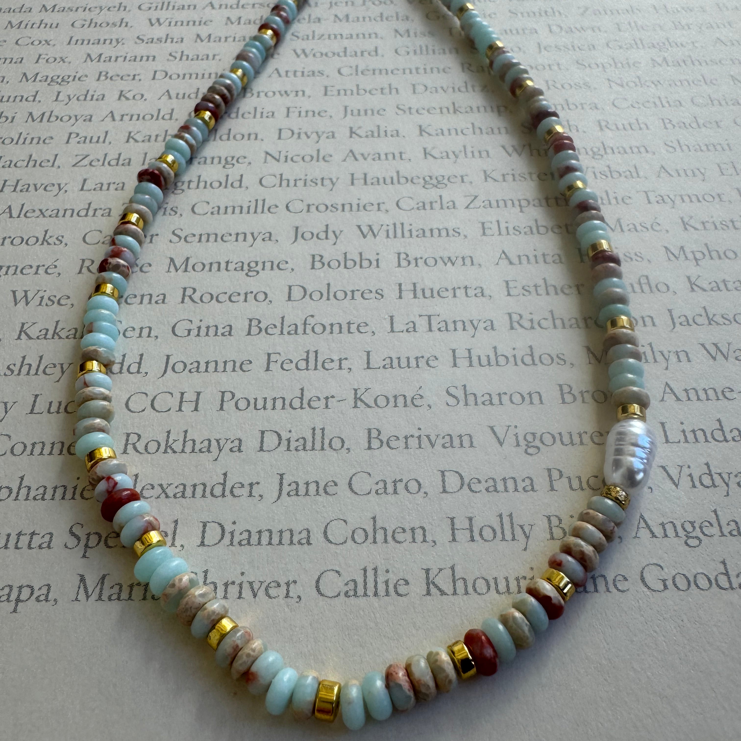 Necklace with multicolored teal, beige and rust orang beads on a textured surface