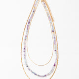 Multistrand beaded necklace with gold chain and clear beads on a white background