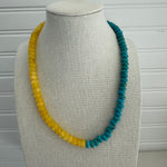 Picture of a bead necklace that is two colors. One half is a bold sunflower yellow and the other turquoise.